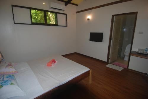 a bedroom with a bed and a window and a television at Rene's Diverslounge Resort in Calape