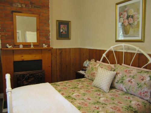 a bedroom with a bed and a fireplace and a mirror at Arendon Cottage in Evandale