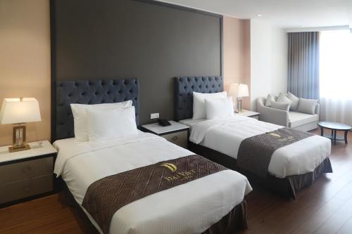 a hotel room with two beds and a chair at Dai Viet Hotel in Thanh Hóa