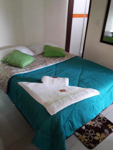 a bed with green pillows and towels on it at Vivienda Turistica Yerbabuena in Filandia