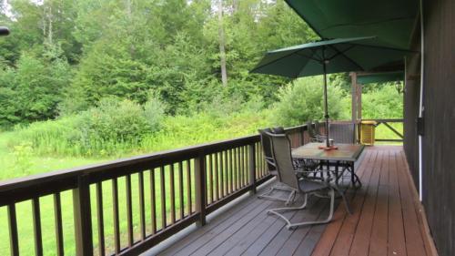 a deck with a table and chairs and an umbrella at Tug Hill Resort in Redfield
