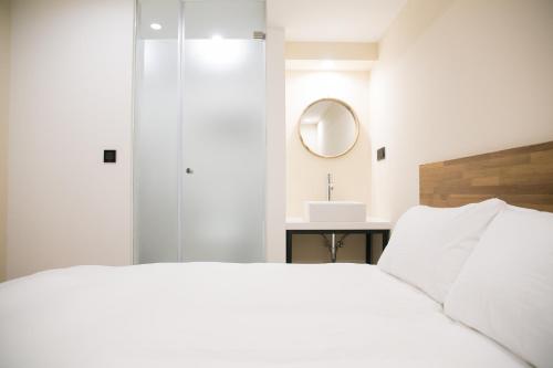a bedroom with a white bed and a mirror at We Come Hostel in Taipei
