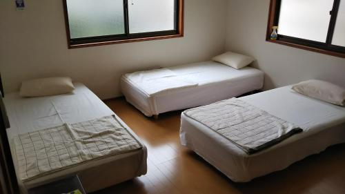 a bedroom with two beds and two windows at Kyoto Narutaki Keisenso in Kyoto