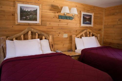 two beds in a room with wooden walls at Georgetown Mountain Inn in Georgetown