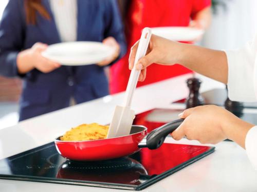 a person is stirring a bowl of food with tongs at Novotel Abu Dhabi Gate in Abu Dhabi