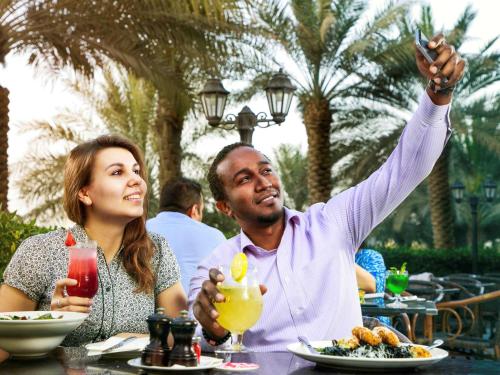 a man and a woman sitting at a table eating food at Novotel Abu Dhabi Gate in Abu Dhabi