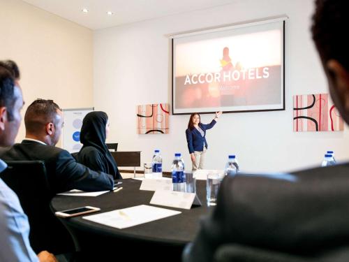 a group of people sitting around a table in a conference room at Novotel Abu Dhabi Gate in Abu Dhabi