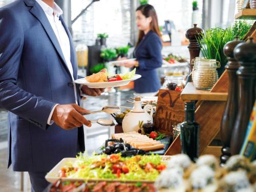 a man holding a plate of food in a buffet at Novotel Abu Dhabi Gate in Abu Dhabi
