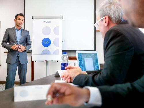 two men sitting at a table in front of a presentation at Novotel Abu Dhabi Gate in Abu Dhabi
