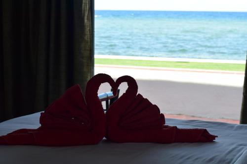 two red swans sitting on a bed with a window at the beachhouse in Dalaguete