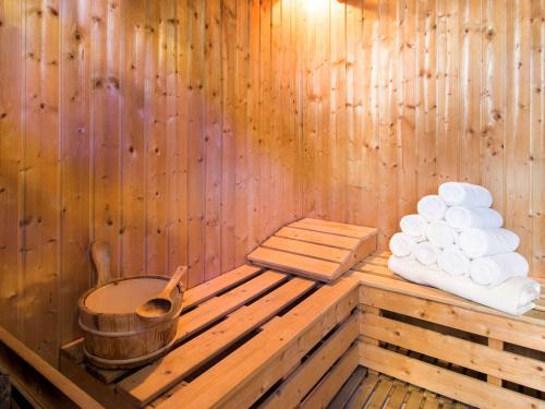 a wooden sauna with a bucket and a stack of towels at Novotel Abu Dhabi Gate in Abu Dhabi