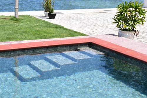 a swimming pool with a red tile floor and water at the beachhouse in Dalaguete