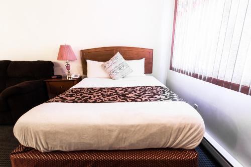 a bedroom with a bed and a chair and a window at Grandview Motel in Kamloops