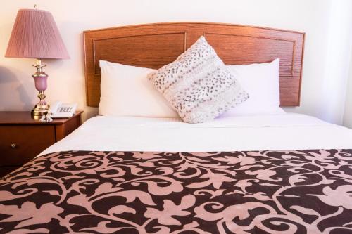 a bed with a black and white comforter and a pillow at Grandview Motel in Kamloops