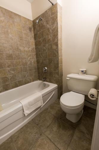a bathroom with a toilet and a tub and a sink at Grandview Motel in Kamloops