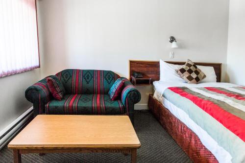 a bedroom with a bed and a couch and a chair at Grandview Motel in Kamloops