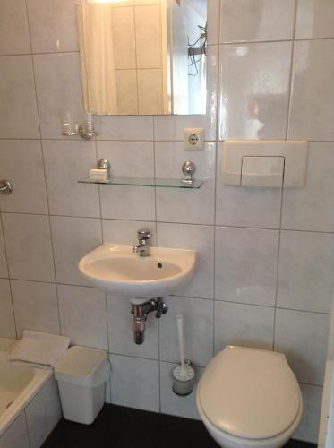 a white bathroom with a sink and a toilet at Hotel Pension Oranje in Valkenburg