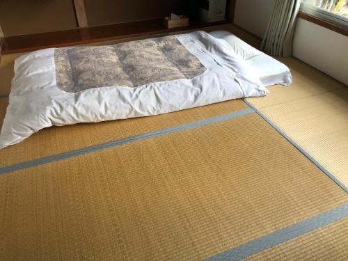 a bed sitting on top of a floor at Guest House Itokawa in Matsuzaki