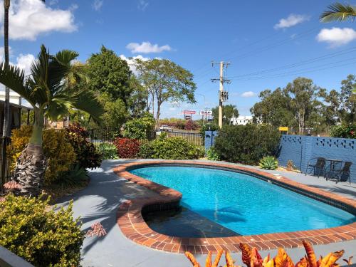 a swimming pool in a yard with a palm tree at True Blue Motor Inn in Rockhampton