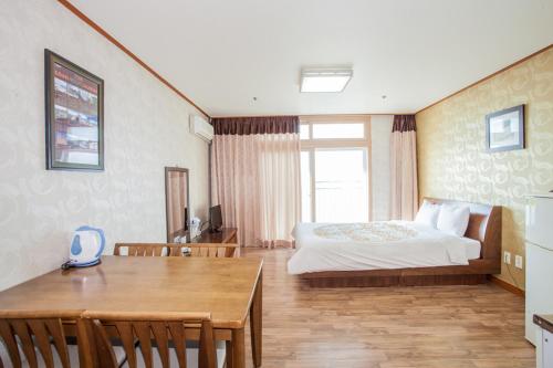 a bedroom with a bed and a table and a dining room at Jeju Ilsung Beach Condo in Jeju