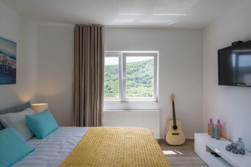 a bedroom with a bed with a television and a guitar at Apartman Nada in Sinj