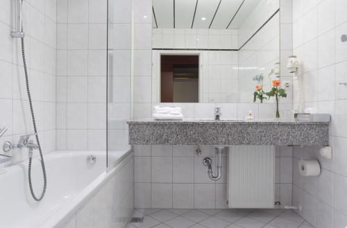 een badkamer met een bad, een wastafel en een douche bij Hotel Alexandersbad in Bad Alexandersbad