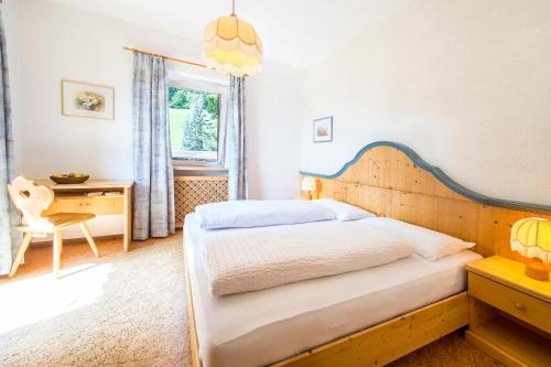 a bedroom with a bed and a desk and a window at Gasthof Wieser in Appiano sulla Strada del Vino