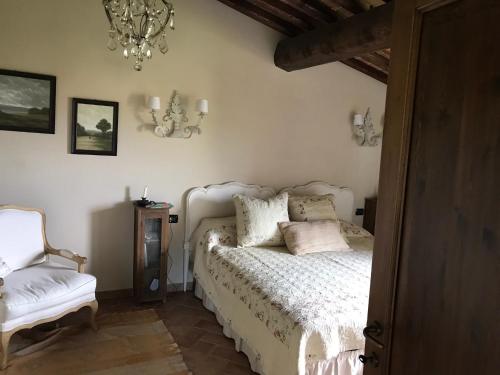 1 dormitorio con 1 cama, 1 silla y 1 lámpara de araña en La Casa del Tatone, en Gambassi Terme