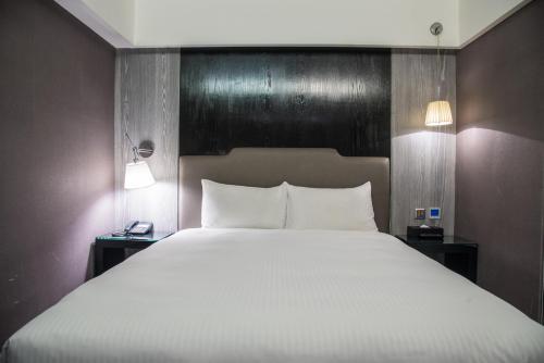 a bedroom with a large white bed with two lamps at The Cloud Hotel in Kaohsiung