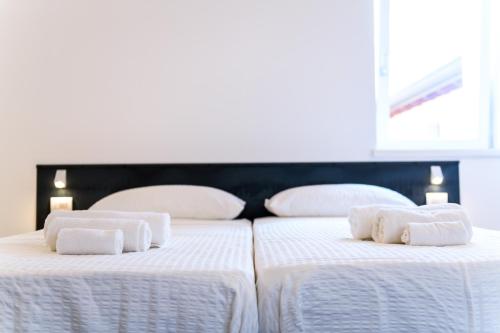 two beds in a room with white sheets and towels at Casa Kaki in Malcesine