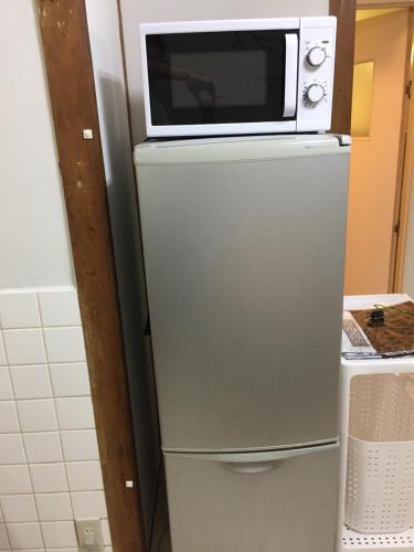 a microwave sitting on top of a refrigerator at Fukuoka Condominium in Fukuoka