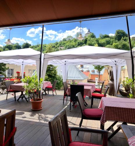 a deck with tables and chairs and white umbrellas at Hotel & Penzión Grand Matej in Banská Štiavnica