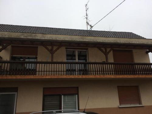 a house with a balcony with a car parked in front at les gites de l'océan indien in Batzendorf