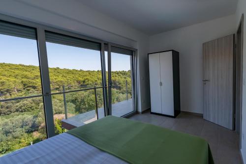 a bedroom with a bed and large windows at Premantura Resort - Hotel & Restaurant in Premantura