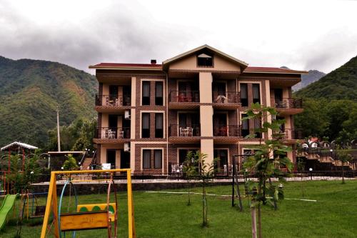 a large building with a playground in front of it at Bergs Hotel And Restaurant in Qax