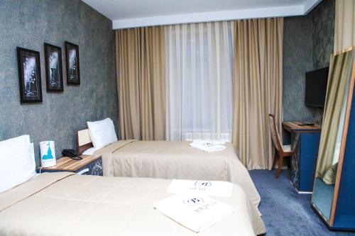 a hotel room with two beds and a television at Bergs Hotel And Restaurant in Qax