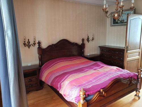 a bedroom with a wooden bed with a pink blanket at les gites de l'océan indien in Batzendorf