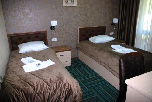 two beds in a hotel room with towels on them at Bergs Hotel And Restaurant in Qax