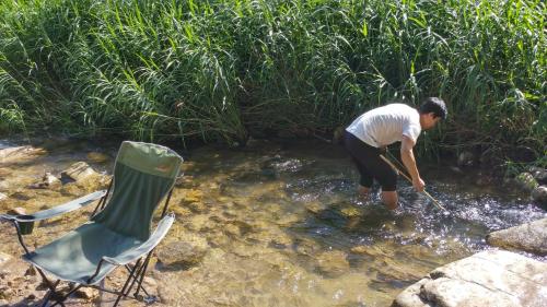 a man standing in the water with a stick at Sisilli Pension in Pyeongchang 