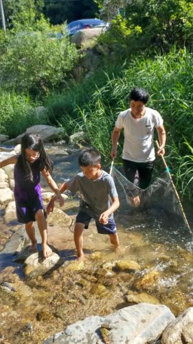 a man and two children playing in the water at Sisilli Pension in Pyeongchang 