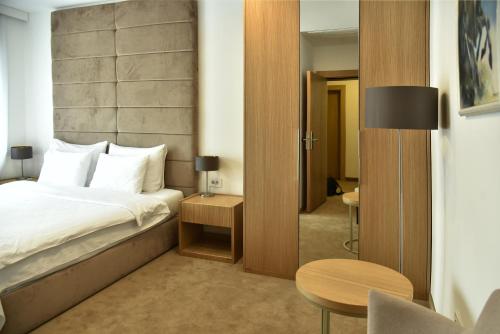 a bedroom with a bed and a table and a chair at Miznah Hotels & Resorts in Bačka Topola