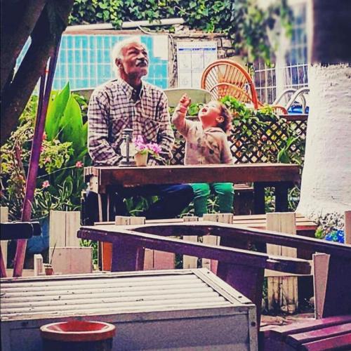 an older man sitting at a table with a child at Side Tuana Garden Home in Side
