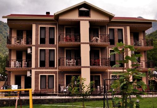 a large brick building with balconies and tables at Bergs Hotel And Restaurant in Qax