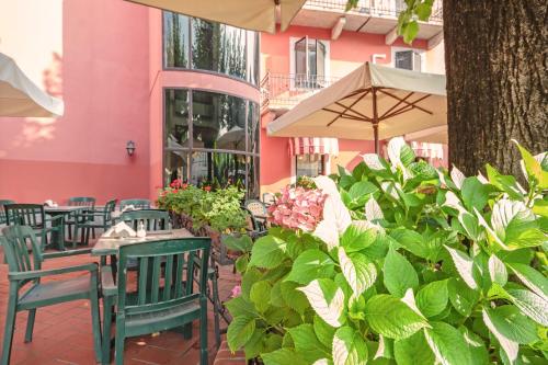 an outdoor patio with tables and chairs and flowers at Albergo Rondò in Acqui Terme