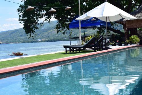 a swimming pool with a table and an umbrella at the beachhouse in Dalaguete