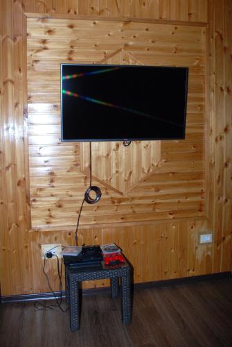 a flat screen tv on a wooden wall with a table at Bergs Hotel And Restaurant in Qax