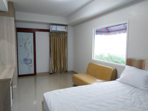 a bedroom with a bed and a chair and a window at Roseate Bangkok Hotel in Bangkok