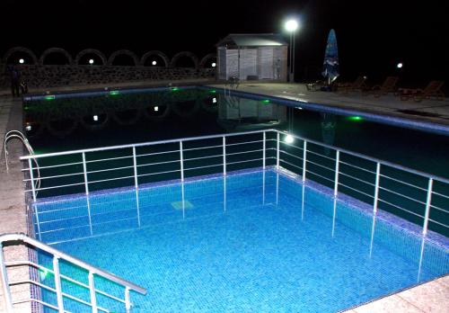 a large swimming pool with blue water at night at Bergs Otel And Restaurant in Qax