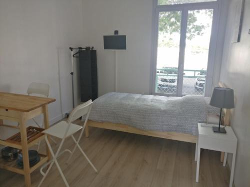 een slaapkamer met een bed en een tafel en stoelen bij Appart Hôtel L'Angélique in Saint-Nazaire