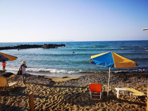 a beach with chairs and umbrellas and the ocean at Anthoula Sunrise in Kokkíni Khánion